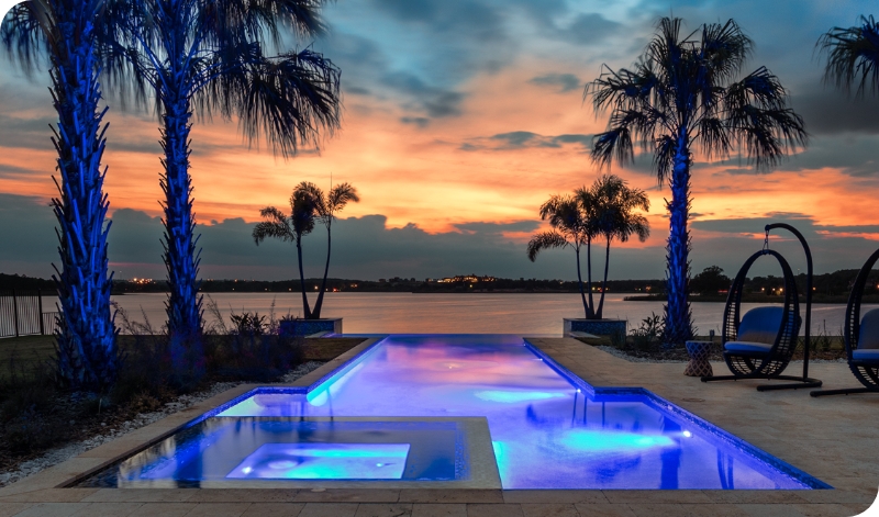 Sunset in distance with lighted pool of purple and blue lights